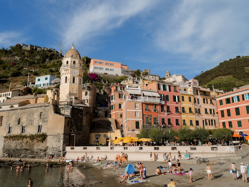 A vibrant picture of the coastline of Monterosso, Italy, with many colored buildings overlooking the water