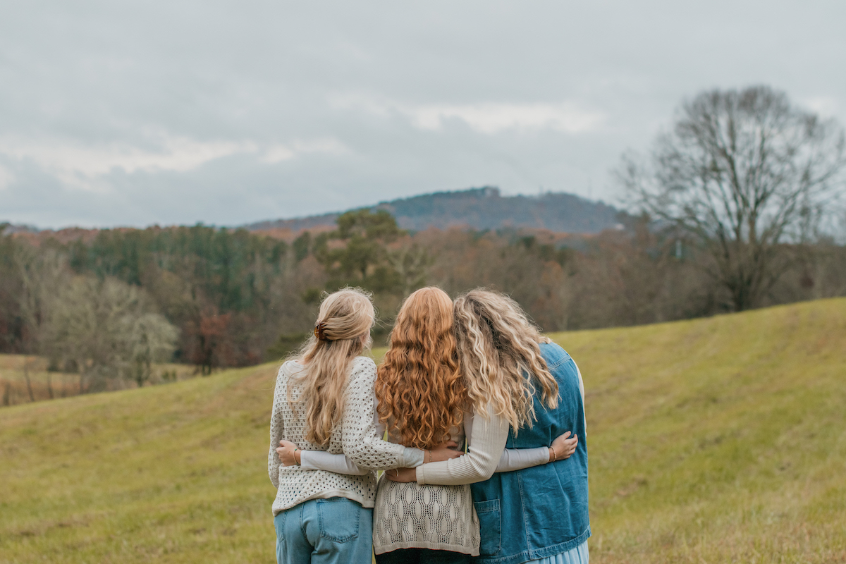 three girls facing a mountain