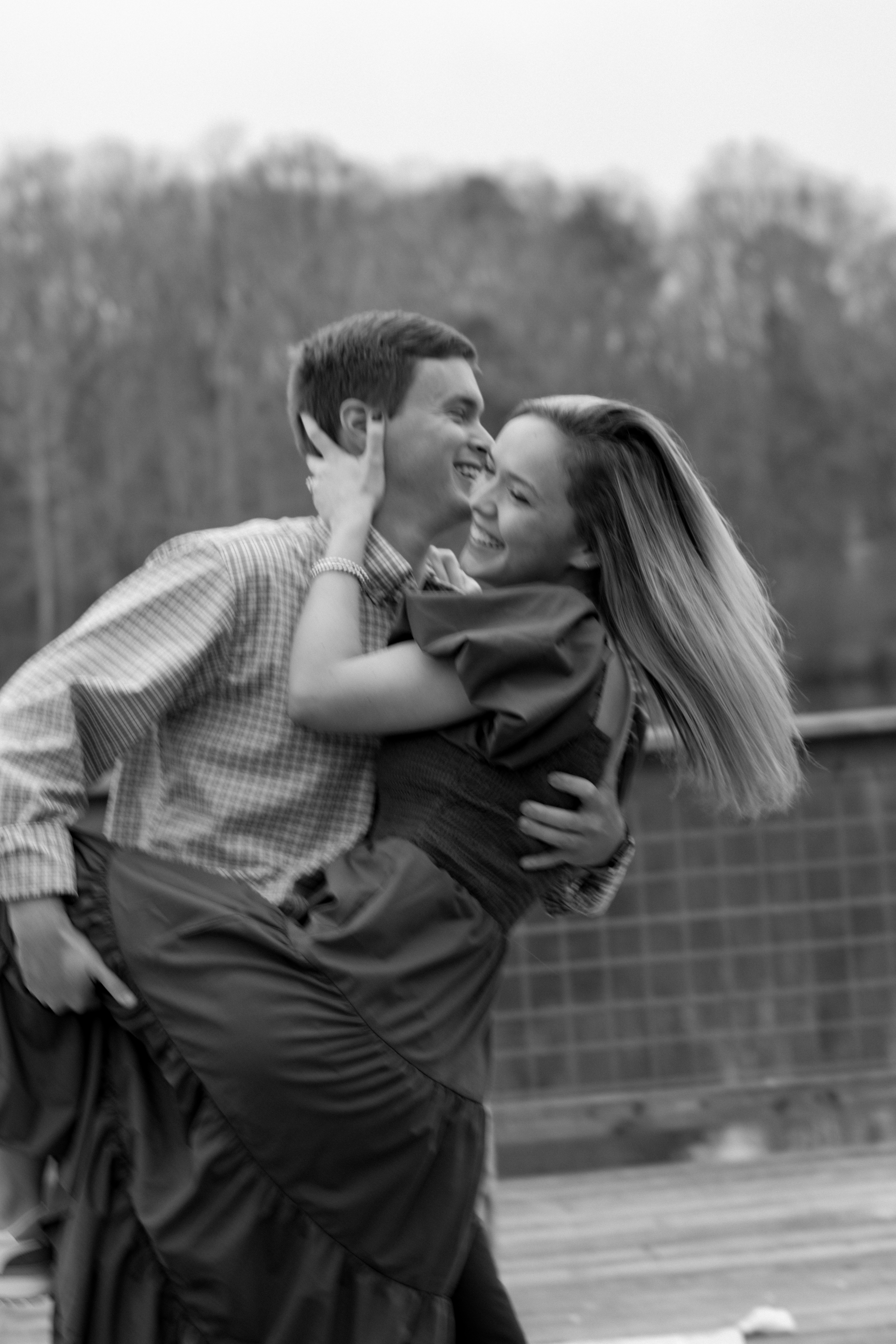 a black and white photo of a couple in motion, the guy kissing the girl on the cheek