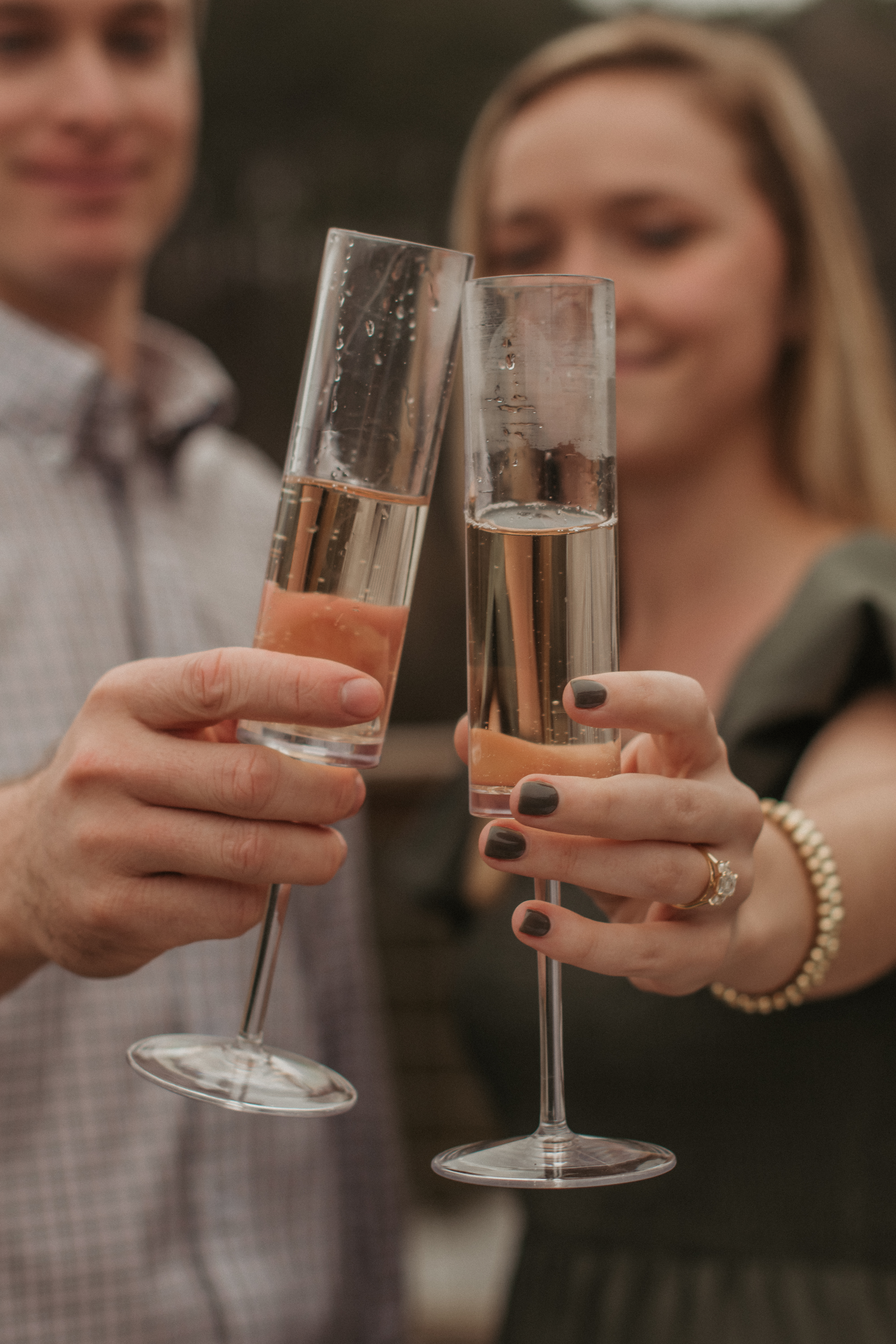 a close shot of champagne being toasted by two people who just got engaged