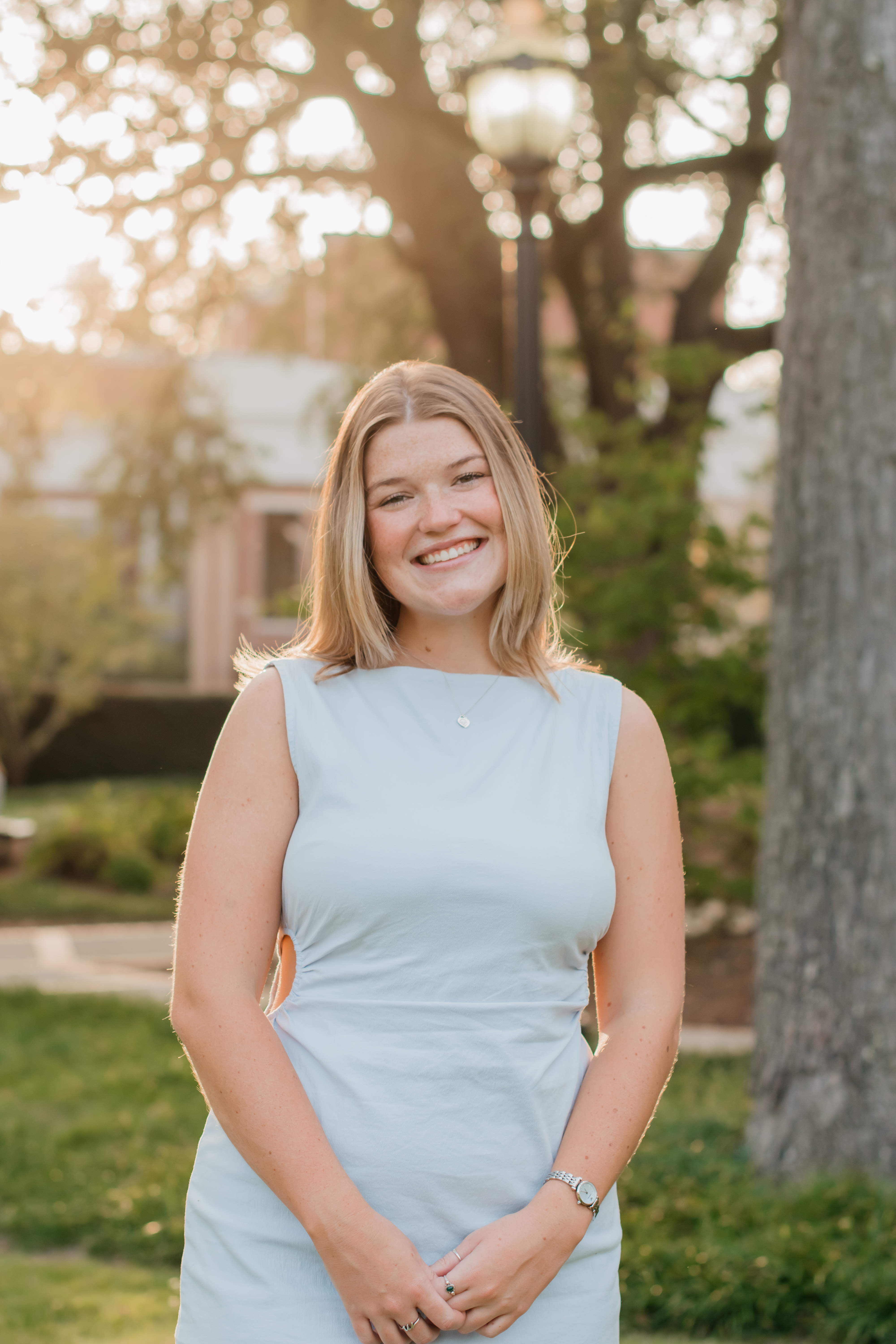 a girl in a pale blue dress standing on the sunny lawn of the GCSU campus