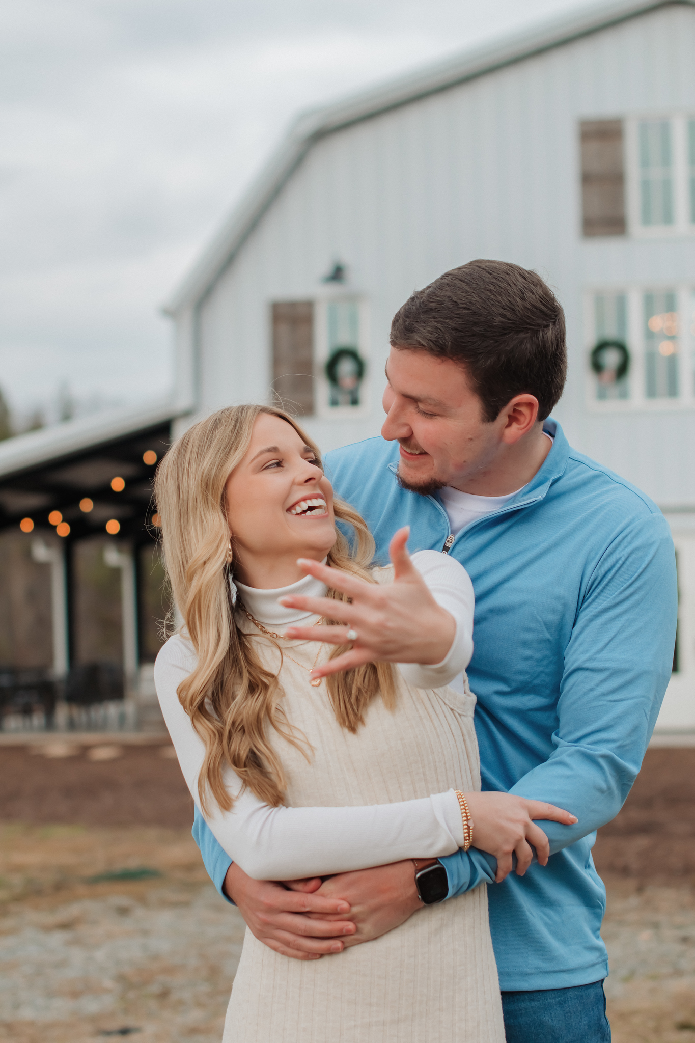 a couple that just got engaged, the guy is hugging the girl and the girl is holding her ring up to the camera